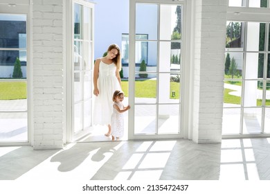 Mom And Child Enter From The Courtyard Into The Open Glazed Door Of The House. Large Spacious Room With High Floor-to-ceiling Windows Letting In The Sun Rays. Choosing And Buying A New Apartment 