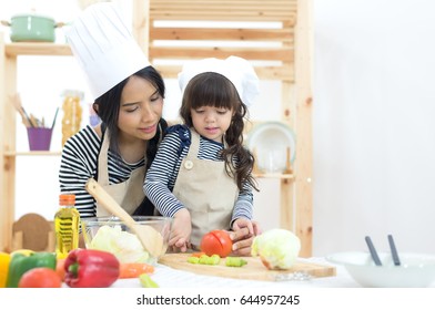 Mom And Child Girl Cooking And Cutting Vegetables On Kitchen.  Healthy Concept