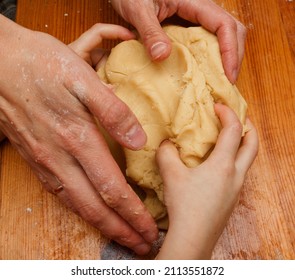 Mom And Child Kneading  Dough For Cookies On Wooden Table