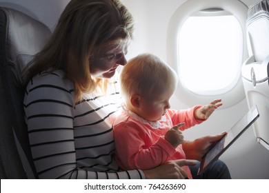 Mom And Child Playing Tablet While Flying On Plane