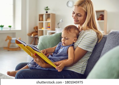 Mom and child are reading a book while sitting on the couch at home. Mothers Day.
