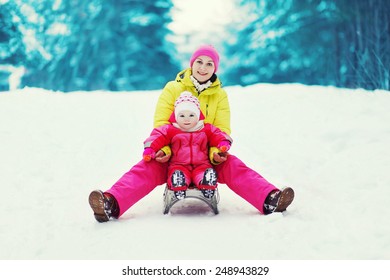 Mom With A Child Sledding And Having Fun In Winter Day