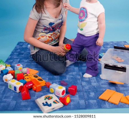 Mom with a child and toys in the studio. Blue background.	