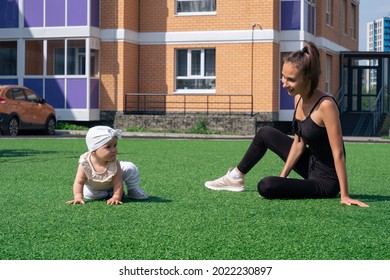 mom and child walk in the city courtyard, child is trying to get up on his own