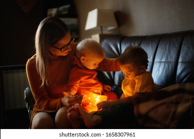 Mom And Children Hugging Together On The Couch. Mom Hugs And Comforts The Siblings. Jealousy And Sibling Relationships Dark Style