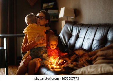 Mom And Children Hugging Together On The Couch. Mom Hugs And Comforts The Siblings. Jealousy And Sibling Relationships Dark Style