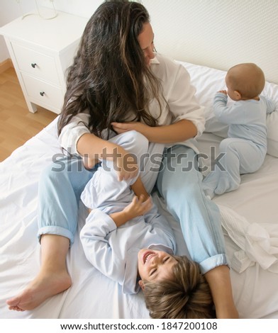 Similar – Relaxed mother and sons playing over the bed