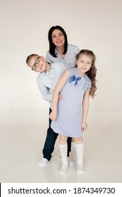 Mom And Children With Special Needs Stand Behind Each Other Smiling While Playing A Game On A White Background. Happy Children. Have A Great Time. A Concept For Helping Children With Special Needs. 