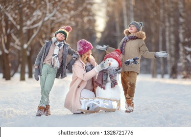 Mom And Children In The Winter Forest Play Snowballs And Make A Snowman. Walking In The Winter Holidays.