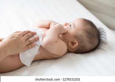 Mom cleaning up and wipe body baby by wet tissue when changing nappies or diaper and wiping the hands or face or leg, Personal hygiene for mother and Toddler kid with wet wipes paper concept