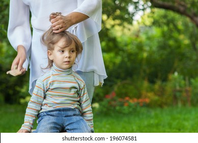 Mom Was Combing Hair With My Little Daughter In Summer Garden.