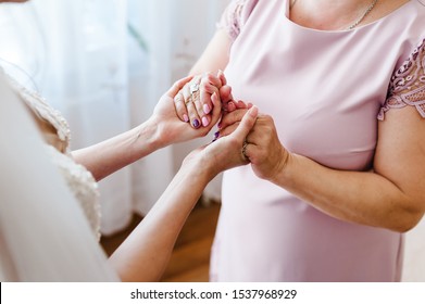 Mom congratulates the bride with a marriage and hold hands. woman welcomes. Wedding day holding. Concept of relationship between moms and daughters. Close up