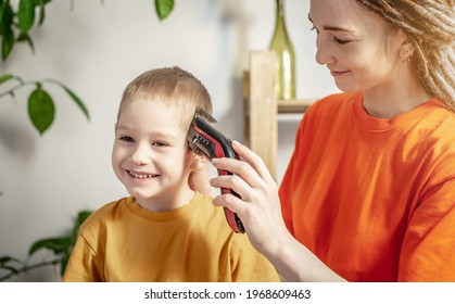 Mom is cutting the child's hair at home using a hair clipper. The little boy is smiling and in a good mood. Concept of family and care. - Powered by Shutterstock