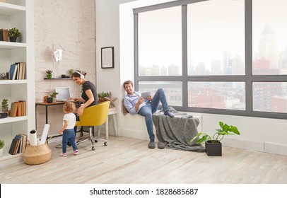 Mom Dad And Baby In The Living Room Spend Time, Mother Is Working And Dad Is Looking Tablet.