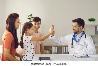 Mom, Dad And Child Seeing Family Doctor At His Office. Happy Girl High-fiving Friendly Pediatrician. Concept Of Healthcare For Children, Trust, Little Patients' Positive Attitude To Visiting Hospital