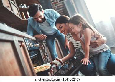 Mom, Dad And Daughter Are Cooking On Kitchen. Happy Family Concept. Handsome Man, Attractive Young Woman And Their Cute Little Daughter Are Making Pizza Together.