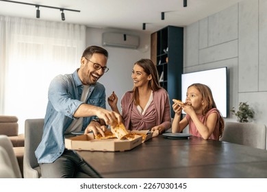 Mom, dad and daughter are eating pizza together at home.Happy family concept. - Powered by Shutterstock