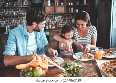 Mom, Dad And Daughter Are Eating Together On Kitchen. Happy Family Concept.