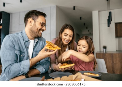 Mom, dad and daughter are eating together at home. Happy family enjoying at home.Family eating pizza at home. - Powered by Shutterstock