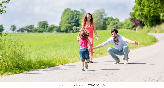 Mom, Dad And Daughter Having Walk On Path In Summer