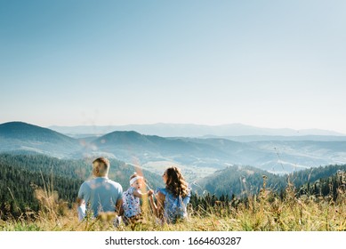 Mom, dad and daughter in the mountains enjoy and look at nature. Back view. Young family spending time together on vacation, outdoors. The concept of family summer holiday. - Powered by Shutterstock