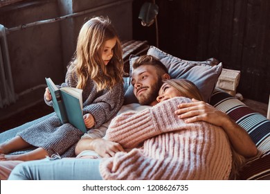 Mom, dad and daughter reading storybook together while lying on bed. - Powered by Shutterstock