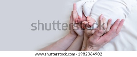 Mom and dad hands hold small legs of their two newborn twin babies. extracorporeal fertilization. multiple pregnancy