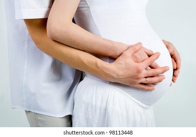 Mom And Dad With Hands On The Baby, On Gray Background