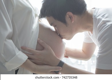 Mom And Dad Hands On Pregnant Tummy Belly. Father Kissing On Wife Belly. Pregnant Couple Caressing Pregnant Belly. Happy Family. Expectant Mother Care. Lovely Family. Asian Family. Pregnancy Mom.