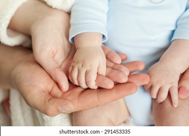 Mom and Dad hold baby's hand - Shutterstock ID 291453335