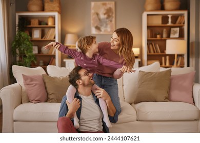 Mom, dad and little daughter playing flying game in the living room - Powered by Shutterstock