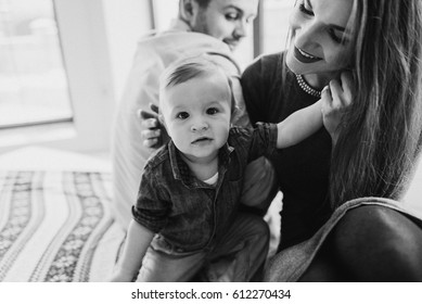 Mom and Dad are playing with their son in the house near the window. Happy family with son. Portrait of a little boy