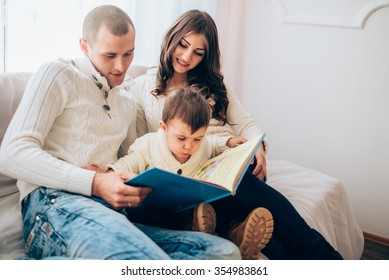 Mom And Dad Read A Book To His Baby Son