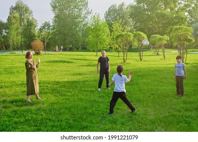 Mama, Papa und Söhne spielen mit einem Fußballball auf der Parkrasen