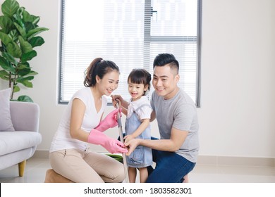 Mom, Dad And Their Little Daughter Cleaning Living Room Together.