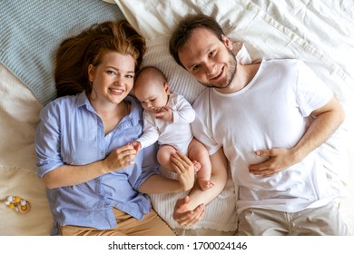 Mom And Dad With A Three Month Old Baby. Beautiful Young Family On Parental Leave. Shot From Above