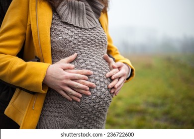 Mom And Dad Touching A Belly With Their Baby, Outside On A Autumn Foggy Day