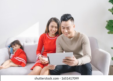 Mom And Dad Usinf Ipad In Living Room.