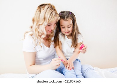 Mom And Daughter In The Bedroom On The Bed In The Curlers Make Up, Paint Their Nails And Have Fun Mom Paints Nails To My Daughter On The Bed