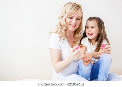 Mom And Daughter In The Bedroom On The Bed In The Curlers Make Up, Paint Their Nails And Have Fun Mom Paints Nails To My Daughter On The Bed