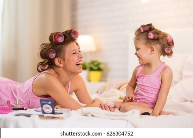 Mom And Daughter In The Bedroom On The Bed In The Curlers Make Up, Paint Their Nails And Have Fun