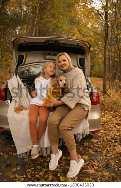 mom with daughter and dog in the car in autumn in\
the forest