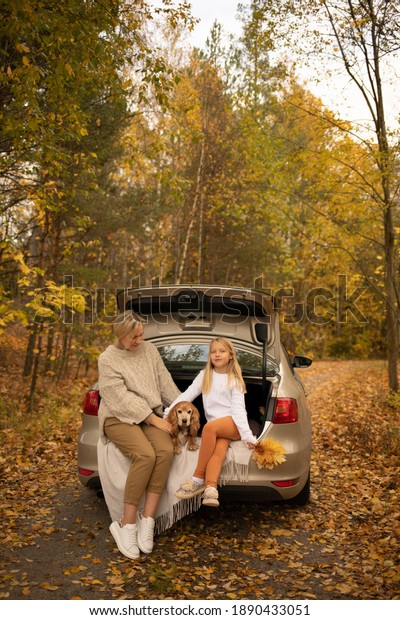 mom with daughter and dog in the car in autumn in\
the forest