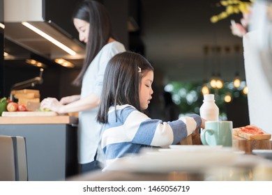 Mom And Daughter Eating Cereals With Milk Having Breakfast In Kitchen.