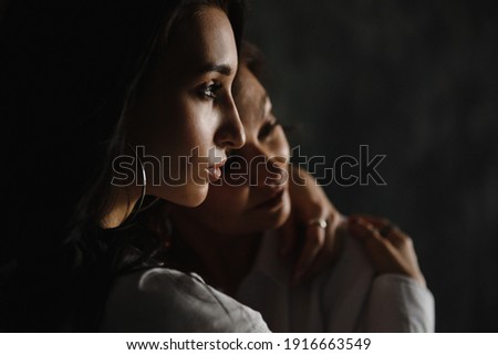 mom and daughter, embrace, on a dark background with natural light