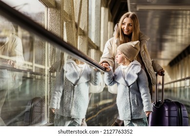 Mom and daughter go up the escalator to the building of the station or airport