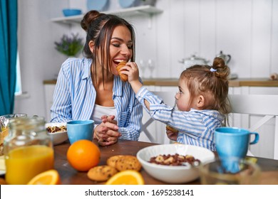 Mom And Daughter Have Breakfast In The Morning At Home. They Eat Cereal And Croissant With Milk.