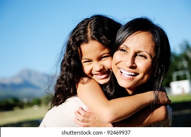 Mom And Daughter Have Fun Outdoors, Smiling And Piggyback In The Sunshine