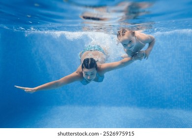 Mom and daughter are immersed in water, swimming under water in a paddling pool. Diving kid. Learning child to swim. Young mother or swimming instructor and happy little girl. - Powered by Shutterstock