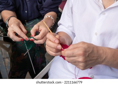 Mom And Daughter Knit Together In The Garden. Family Friendly Leisure. Elderly Mother Teaching To Crochet Adult Daughter 